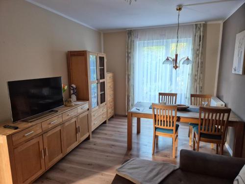 ein Wohnzimmer mit einem Esstisch und einem TV in der Unterkunft Ferienwohnung am Golfplatz in Adorf