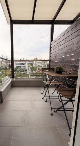 einen Balkon mit einer Holzbank und einem Tisch in der Unterkunft Panorama Sunvilles Apartment 6 in Thessaloniki