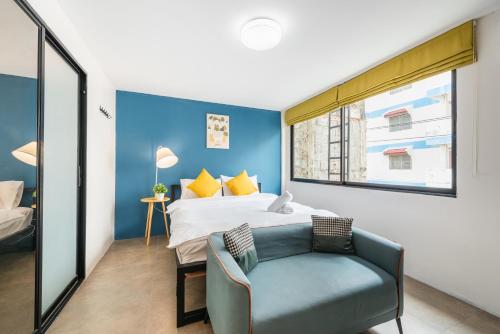 a bedroom with a bed and a chair and a window at Lachata - Hua Mak in Bangkok