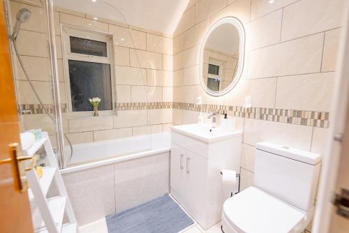 a bathroom with a toilet and a sink and a tub at 4BR 2Bath Home -Hot Tub, Free Parking & Games Room in Cardiff