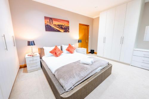 a bedroom with a large white bed with orange pillows at 4BR 2Bath Home -Hot Tub, Free Parking & Games Room in Cardiff