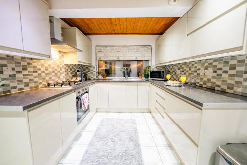 a kitchen with white cabinets and a wooden ceiling at 4BR 2Bath Home -Hot Tub, Free Parking & Games Room in Cardiff