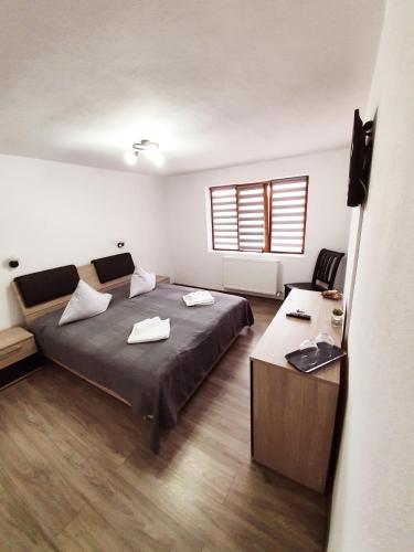 a bedroom with a bed and a desk and a window at Popasul de Sub Munte in Văleni
