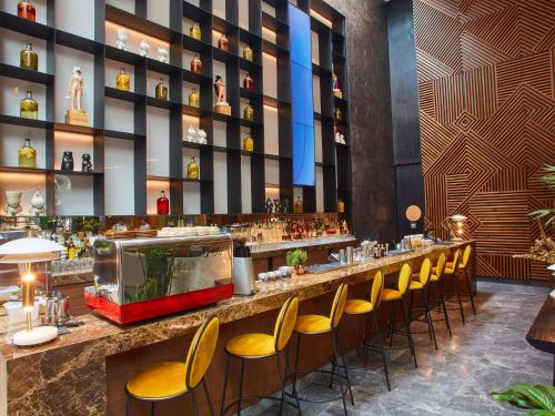 a restaurant with a bar with yellow chairs at Pullman Lima Miraflores in Lima