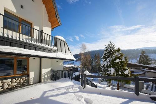 ein Haus mit Balkon mit Schnee auf dem Boden in der Unterkunft EveRest Apartamenty Szczyrk in Szczyrk