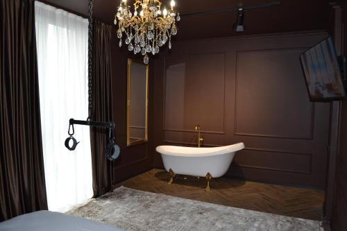 a bathroom with a tub and a chandelier at Park Gate apartment Новий Елітний ЖК біля Центрального парку in Chernivtsi