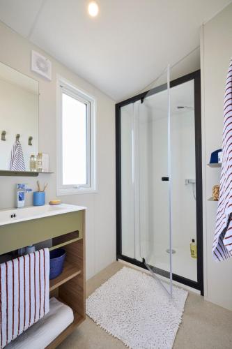 a bathroom with a glass shower and a sink at Camping de la Tour AMBON in Ambon