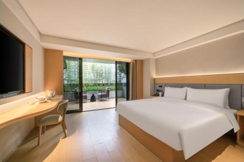 ein Schlafzimmer mit einem großen weißen Bett und einem Schreibtisch in der Unterkunft All Seasons Hotel Guangzhou Wuyangcun Metro Station in Guangzhou