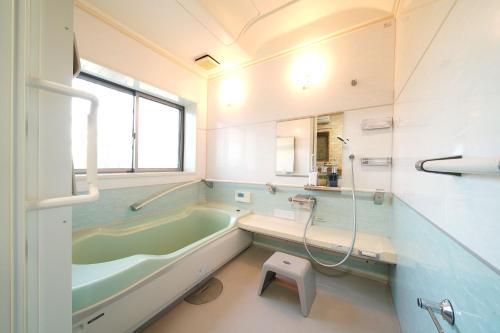 a bathroom with a green tub and a window at 糸島リトリートヴィラ芥屋 in Itoshima