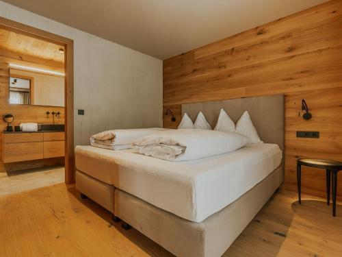 a bedroom with a large white bed and a bathroom at Almrausch Lech Apartments in Lech am Arlberg