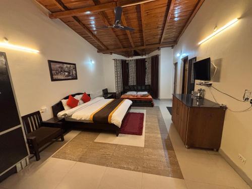 a bedroom with a bed and a dresser and a television at Hotel Goludev Valley View in Nainital