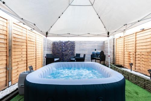 a large hot tub in a patio with a table at Open Mind Property - 4 BR, Hot Tub & Free Parking in Portsmouth
