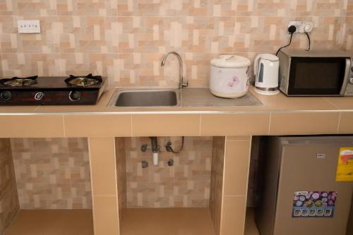 un comptoir de cuisine avec un évier et un micro-ondes dans l'établissement Guest Apartments, à New Weija