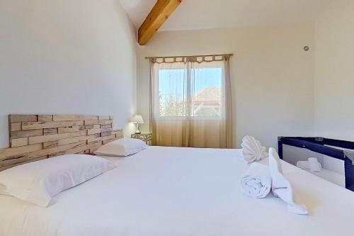 a white bedroom with two beds and a window at CALA CORSICA - Villas 5 Etoiles T5 Piscine privée - Villa T4 Piscine privée chauffée - Villa T3 Piscine partagée - Internet Fibre - Entièrement Climatisée à Lecci de Porto-Vecchio Cala Rossa in Lecci