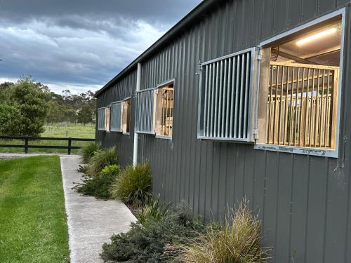 a black building with windows and a sidewalk at Luxury Barn-Style Suite with Stable Views in Gruyere