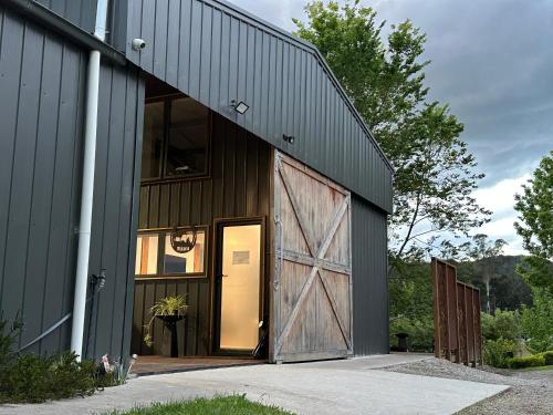 a barn with a large wooden door on the side of it at Luxury Barn-Style Suite with Stable Views in Gruyere