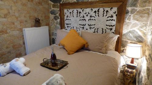 Bett mit einem Tablett mit einer Flasche Wein darauf in der Unterkunft STONE of KAMARIZA in Áyios Konstandínos