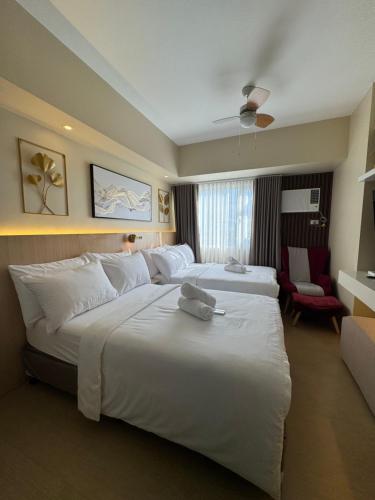 a hotel room with two beds and a chair at Cattleya BNB Rentals 1 at Avida Tower 2, CDO in Cagayan de Oro
