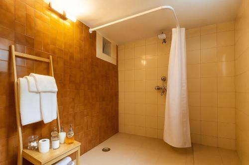 a bathroom with a shower with a white shower curtain at Casa Do Leão - Heritage Boutique Stay in Nerul