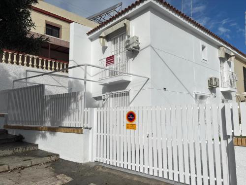 ein weißes Haus mit einem weißen Gartenzaun in der Unterkunft Alojamientos VICTORIA MAR-CHIPIONA- in Chipiona