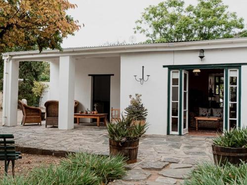 a white house with a patio and a table at Karoo Cypress Guesthouse in Graaff-Reinet