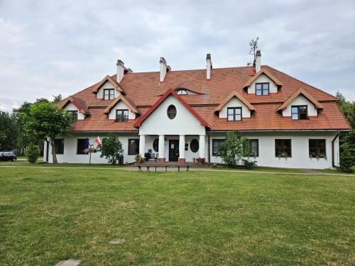 een groot wit huis met een rood dak bij Pokój 105 Comfort 