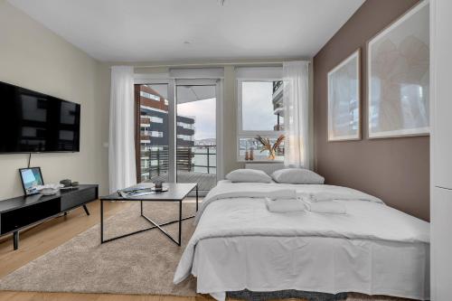 ein weißes Schlafzimmer mit einem großen Bett und einem Schreibtisch in der Unterkunft Northstay - Cozy Arctic Apartment, Free Parking in Tromsø