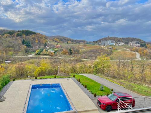 ヴルドニークにあるGreen panorama Vrdnikのプールの隣の道路に駐車された赤い車