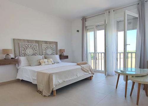 a white bedroom with a large bed and a table at Ría Vale 2 in Santa Marta de Magasca