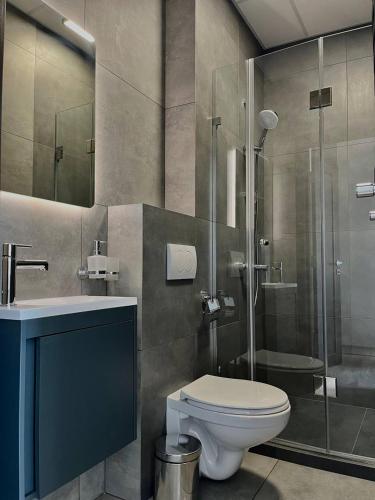 a bathroom with a toilet and a glass shower at Апарт-готель "Модерн 24" in Netishyn