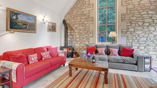 a living room with a red couch and a table at The Stables, Batheaston in Batheaston