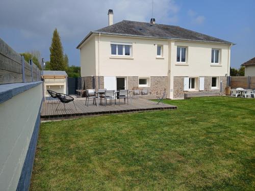 ein großes Haus mit einer Terrasse und einem Hinterhof in der Unterkunft L'Escale du Cu de Loup in Quettehou