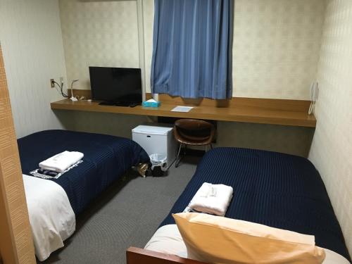 Pokój z 2 łóżkami i biurkiem z komputerem w obiekcie Ribera Inn w mieście Satsumasendai