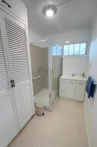 a white bathroom with a shower and a sink at Renovated 3-Bedroom Beach House - Sleeps 9 in Golden Beach