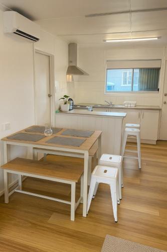 a kitchen with a table and two white stools at Renovated 3-Bedroom Beach House - Sleeps 9 in Golden Beach