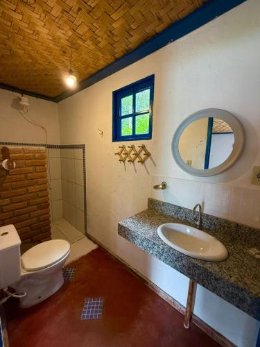 a bathroom with a toilet and a sink and a mirror at Pousada chalés São Geraldo in Lima Duarte