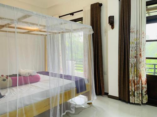 KamburugamuwaにあるMoon View Homestayのベッドルーム1室(天蓋付きベッド1台、窓付)