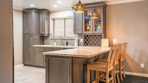 a kitchen with wooden cabinets and a kitchen island with chairs at Walk to Lake 7BDR HotTub Movie Theater GameRoom Dawn and Dusk by AvantStay in Big Bear Lake