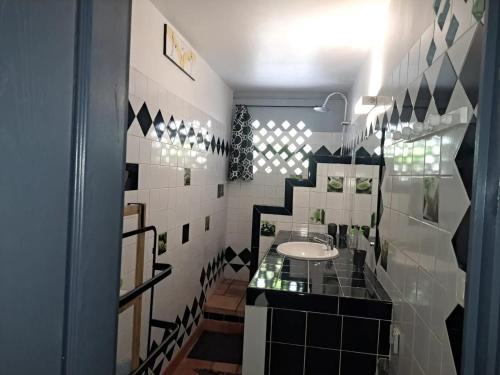 La salle de bains est pourvue de carrelage noir et blanc et d'un lavabo. dans l'établissement Appartement convivial à Sainte-Luce de 60 m² avec jardin, à Trois-Rivières