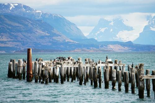 a pier in the water with mountains in the background at 6 personas - Casa amplia y acogedora en zona residencial in Puerto Natales
