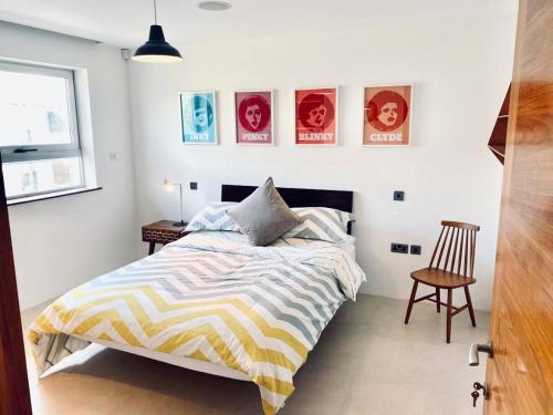 a bedroom with a bed and a chair and pictures on the wall at Eight Water's Edge in Tenby