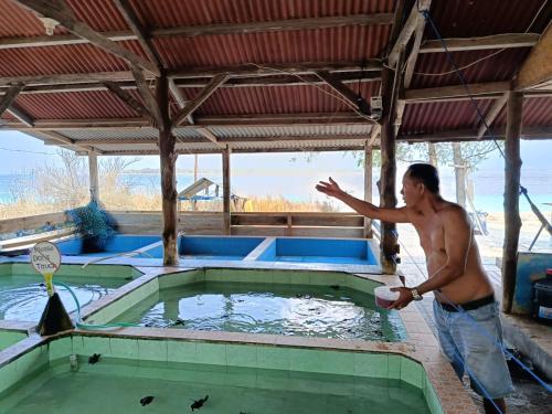 Ein Mann steht mit einer Frisbee in einem Wasserbecken. in der Unterkunft Meno Turtle BUNGALOWS in Gili Meno