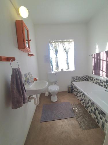 a bathroom with a tub and a toilet and a sink at Vellies Getaway in Buffelspoort