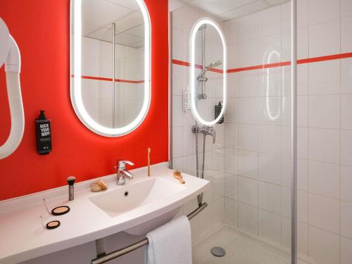 a bathroom with red walls and a sink and a shower at ibis Montélimar Nord in Saulce-sur-Rhône