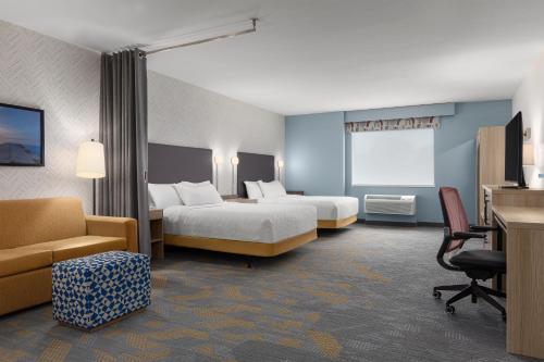 a hotel room with two beds and a couch at Home2 Suites By Hilton Woodstock On in Woodstock