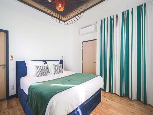 ein Schlafzimmer mit einem Bett mit grün-weißer Bettwäsche in der Unterkunft MADISON Saint Jean de Luz - Handwritten Collection in Saint-Jean-de-Luz