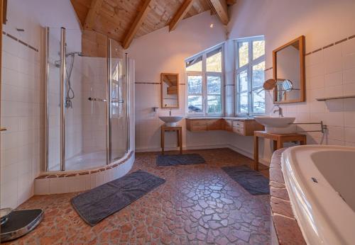 Un baño con dos lavabos, una ducha y una bañera. en Chalet Sendlhofer, en Bad Hofgastein