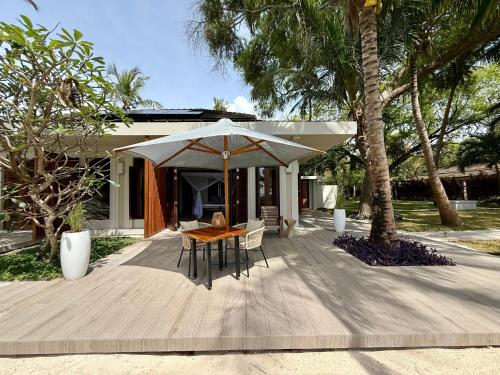 une terrasse en bois avec une table et un parasol dans l'établissement Maya kobe Beachfront Retreat Kilifi, à Kilifi