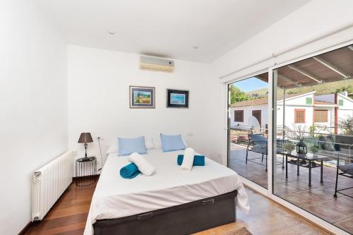 ein weißes Schlafzimmer mit Bett und Balkon in der Unterkunft Casa con piscina y gran jardín in Colònia de Sant Pere