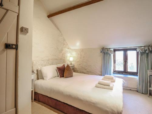 une chambre avec un grand lit blanc avec une fenêtre dans l'établissement 1 Fron Uchaf, à Frongoch